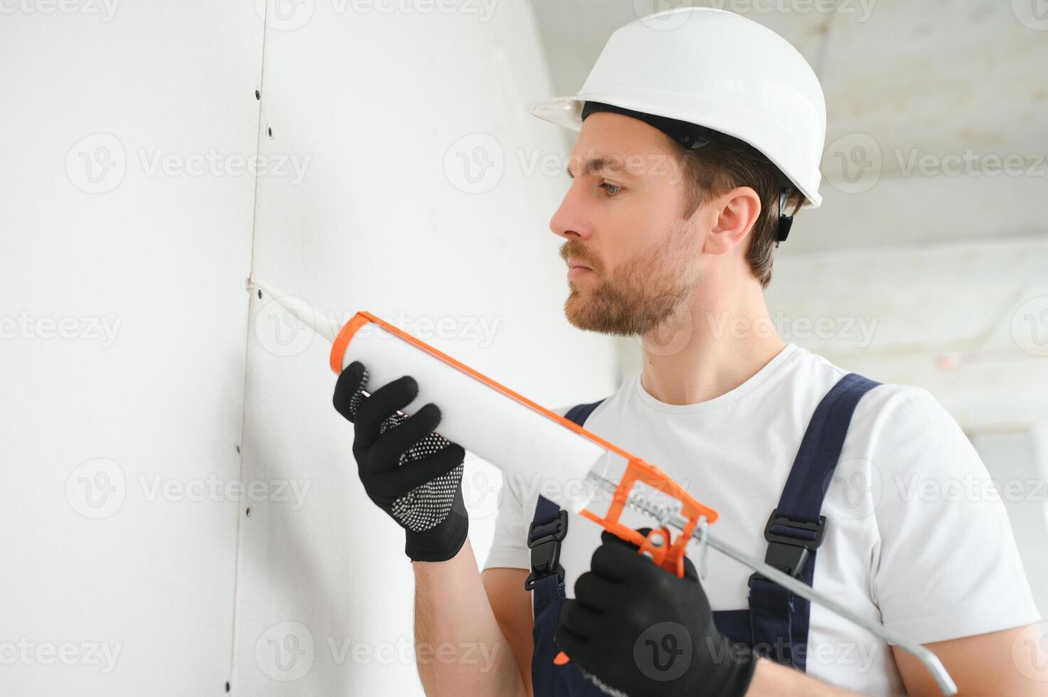 Professional Workman Applying Silicone Sealant With Caulking Gun on the Wall photo