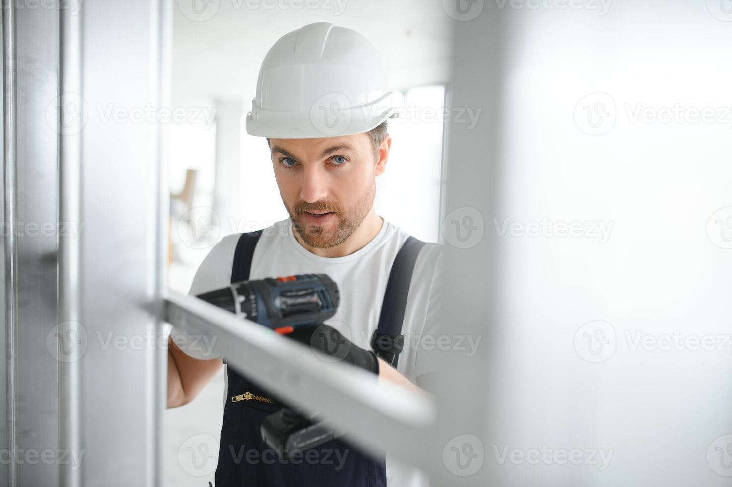 Construction worker installing metal profile for interior partition wall, while building a new house or renovation process, viewed from his back. photo