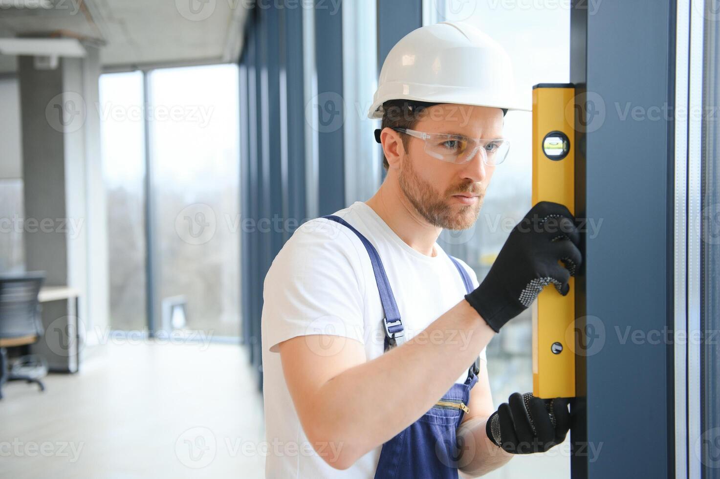 Worker using bubble level after plastic window installation indoors photo