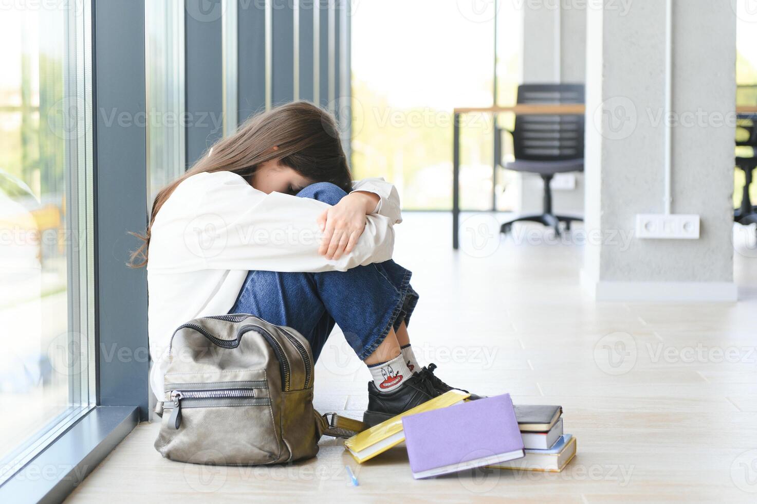 Lonely sad schoolgirl while all her classmates ignored her. Social exclusion problem. Bullying at school concept. photo