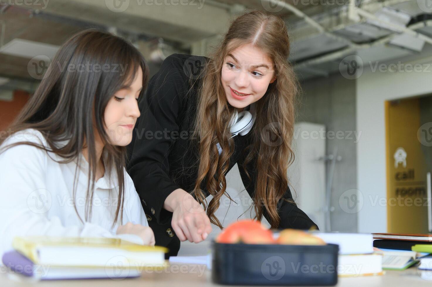 Two students doing homework together and helping each other sitting in a table. photo