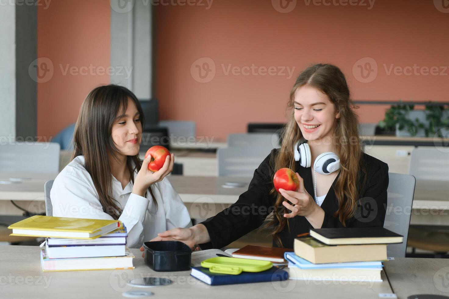 Education. Two clever modern students in black and white uniform study in a library sitting at a table with books. Modern generation. Students. photo