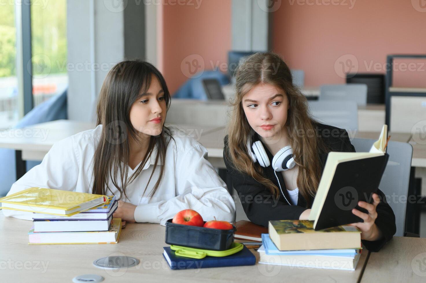 Education. Two clever modern students in black and white uniform study in a library sitting at a table with books. Modern generation. Students. photo