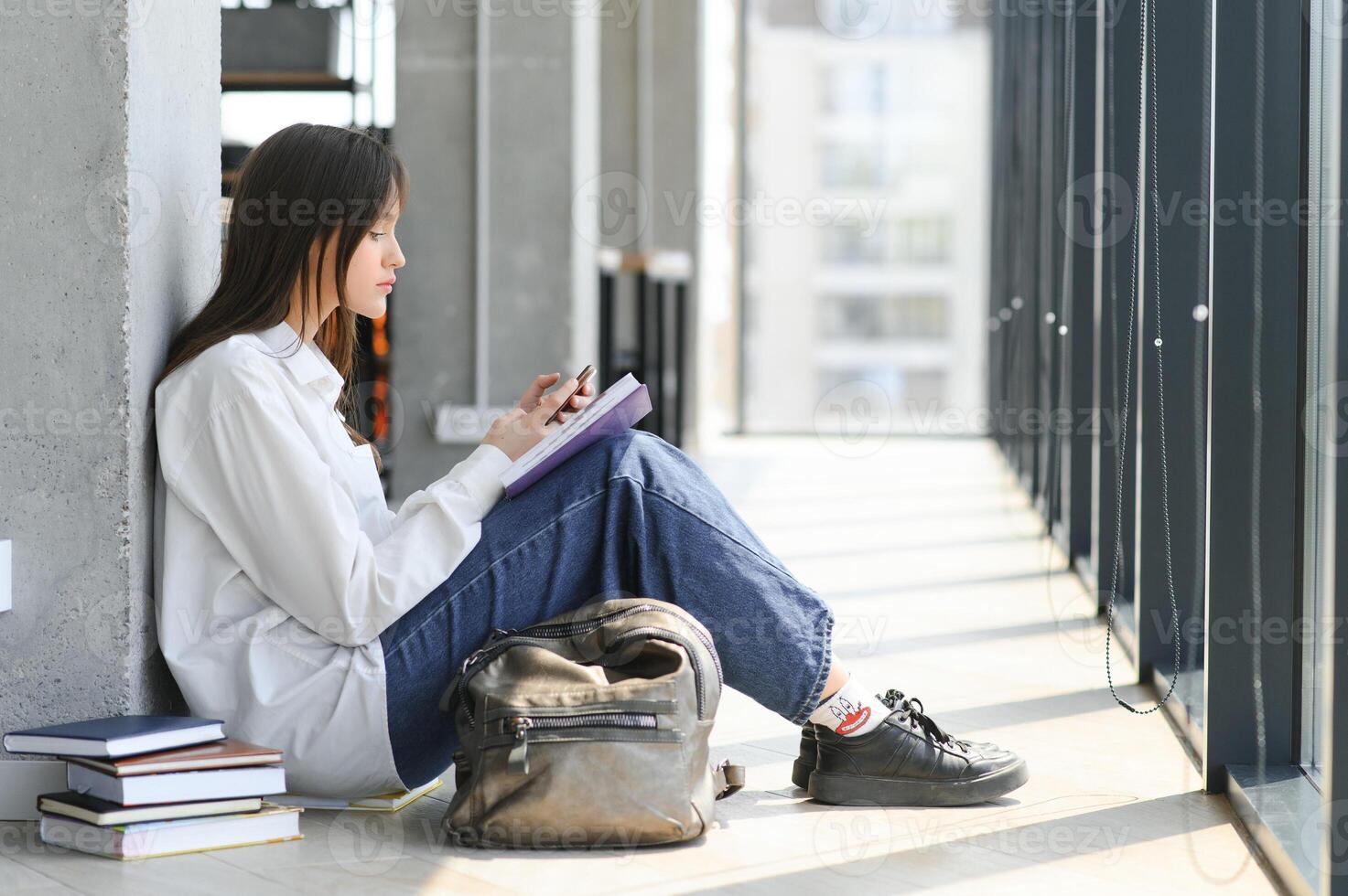 Educational concept. A modern girl student sits on the floor and reading joyfully a book. Modern generation. Reading. photo