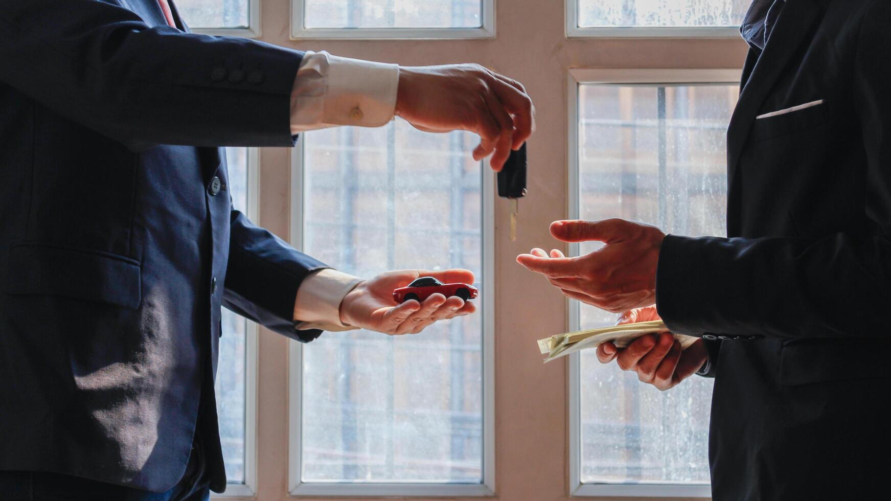 A young businessman enters into a red sports car contract and is accepting the keys from a sports car dealer as a gift to himself for his successful venture. Car trading ideas from trusted dealers. photo