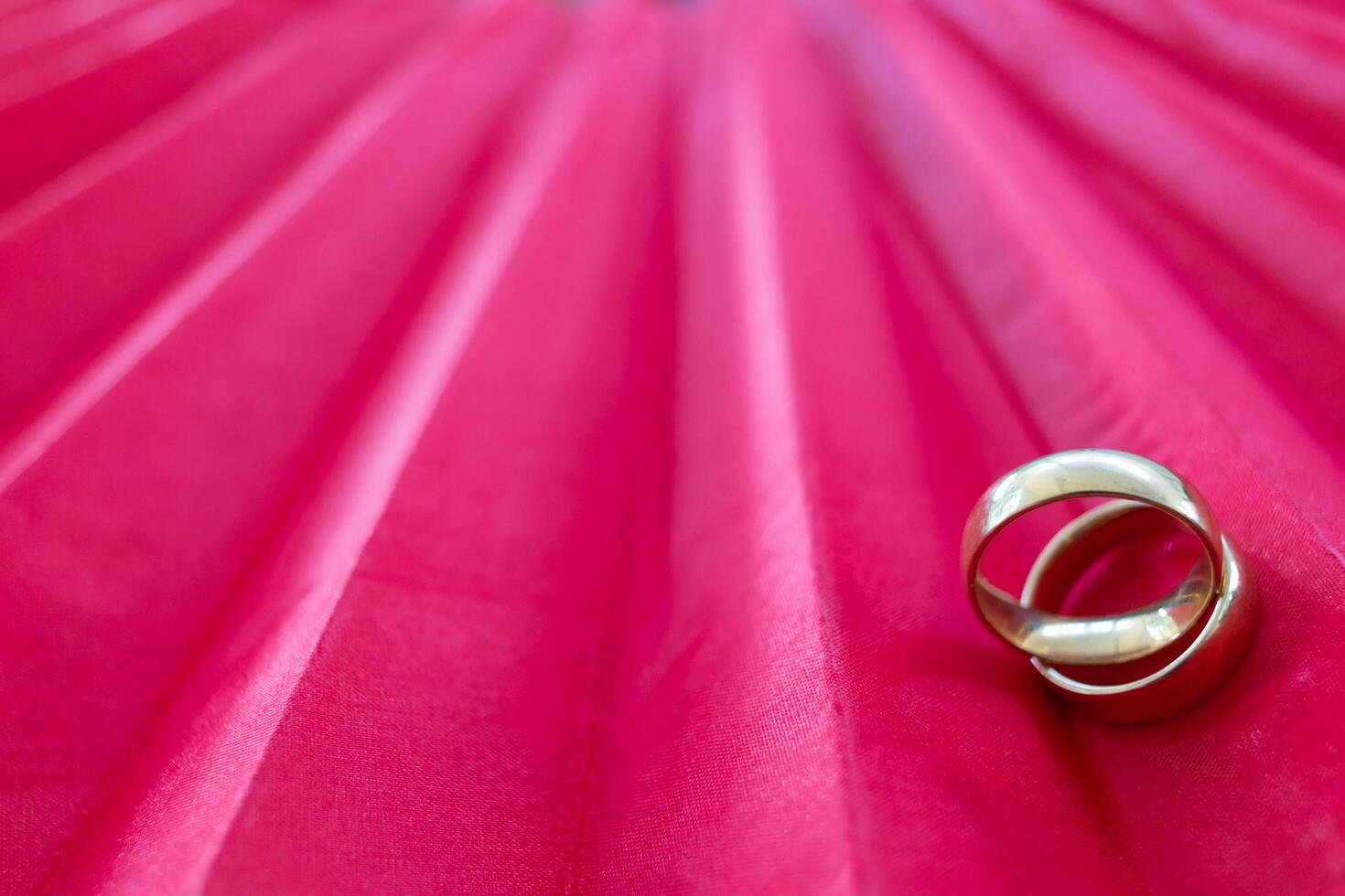 Two gold rings for couples prepared to be given to each other on Valentine's Day on a red background and two gold rings also symbolize promise between lovers to love and care for each other forever. photo