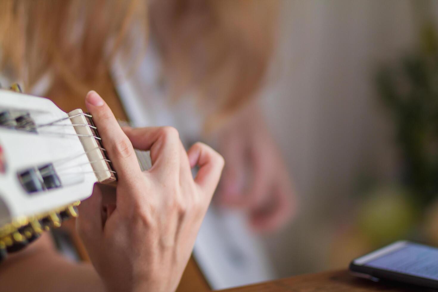 A young woman is practicing acoustic guitar to perform on stage in a music practice room before performing in order to reduce mistakes. Close Up, a woman's hand holding guitar chords for practice. photo