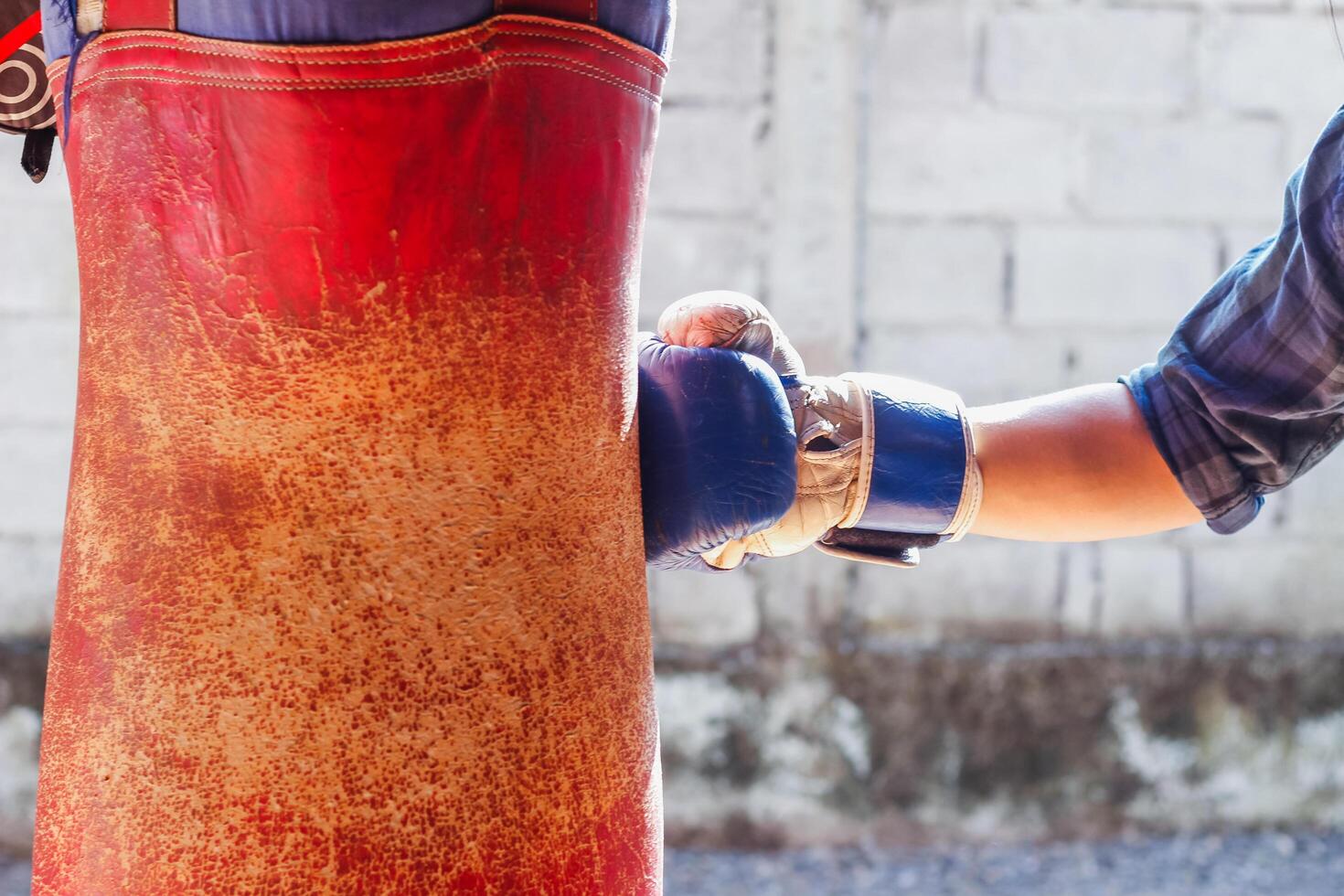 Soft Light and Blur,The young man was wearing a boxing mitt on his hand and punched the sandbag with great force to release his anger. Ideas for venting anger by boxing or punching a sandbag photo