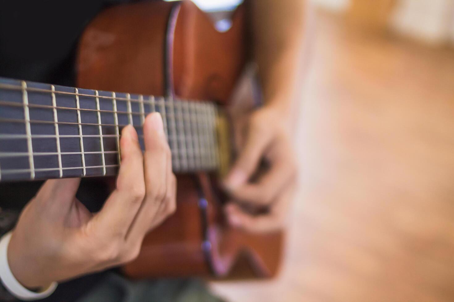 A young man is practicing playing guitar in a music practice room before performing in order to reduce the mistake of playing guitar on stage. Close Up Young man is holding guitar chords for practice. photo