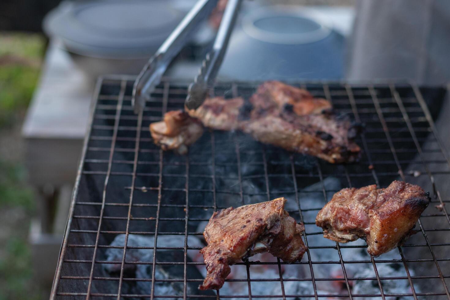 The meat is grilled on a metal grill over charcoal grill to be cooked. It's a fun BBQ during the holidays and out camping with the family. Barbecuing is a popular dish during celebrations and camping. photo