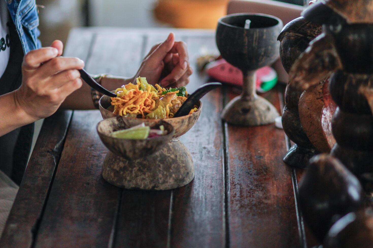 Soft focus,The woman ordered the Khao Soi beef menu from a famous restaurant in Chiang Rai province, which is a Khao Soi menu served in a coconut shell instead of serving the food in a delicious dish. photo