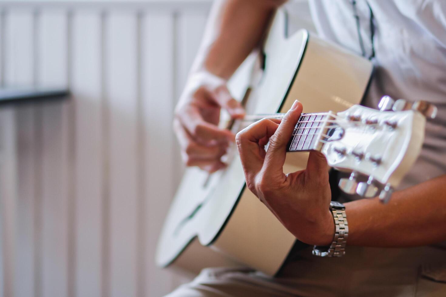 A young man is practicing playing guitar in a music practice room before performing in order to reduce the mistake of playing guitar on stage. Close Up Young man is holding guitar chords for practice. photo