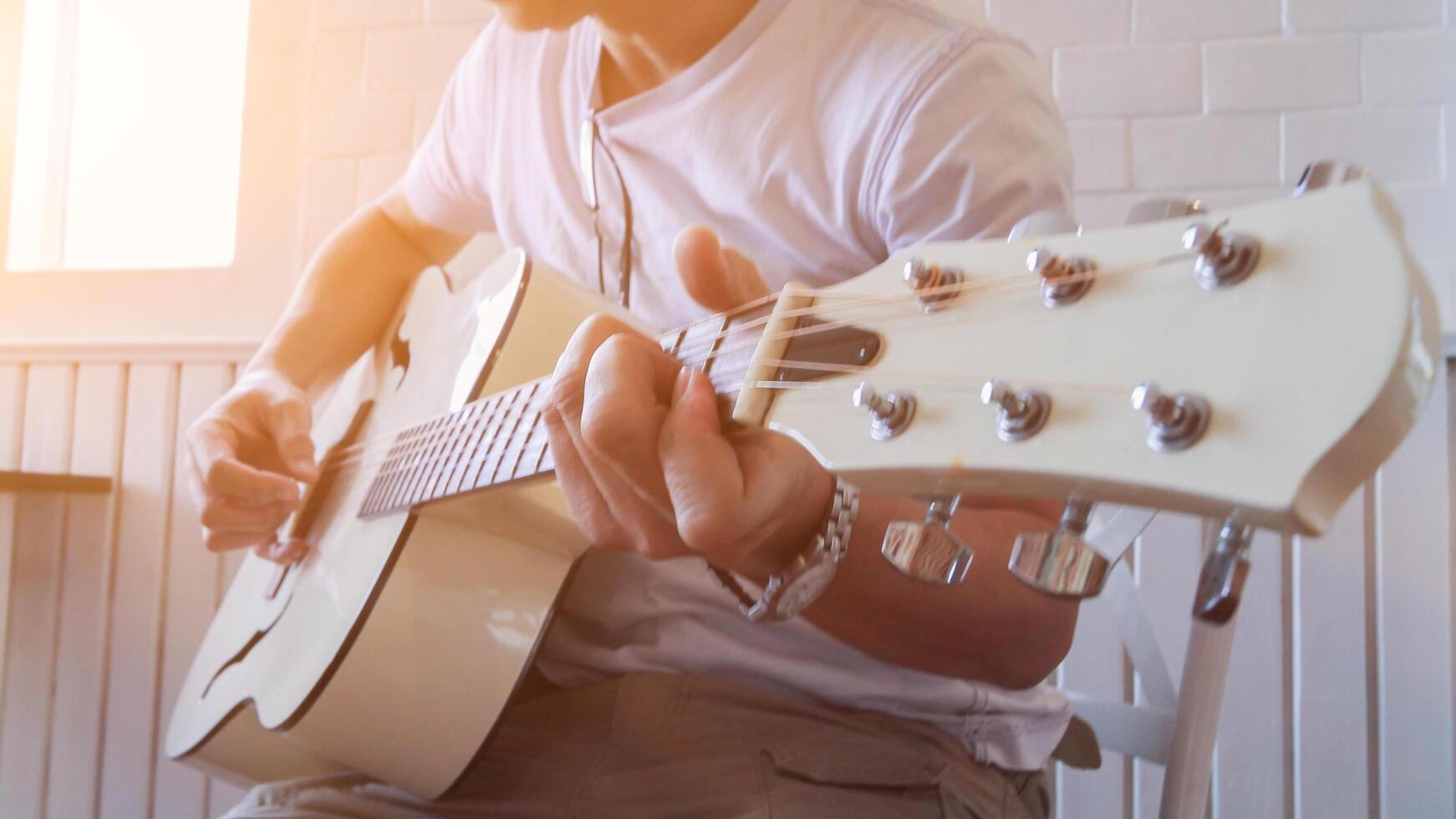 A young man is practicing playing guitar in a music practice room before performing in order to reduce the mistake of playing guitar on stage. Close Up Young man is holding guitar chords for practice. photo
