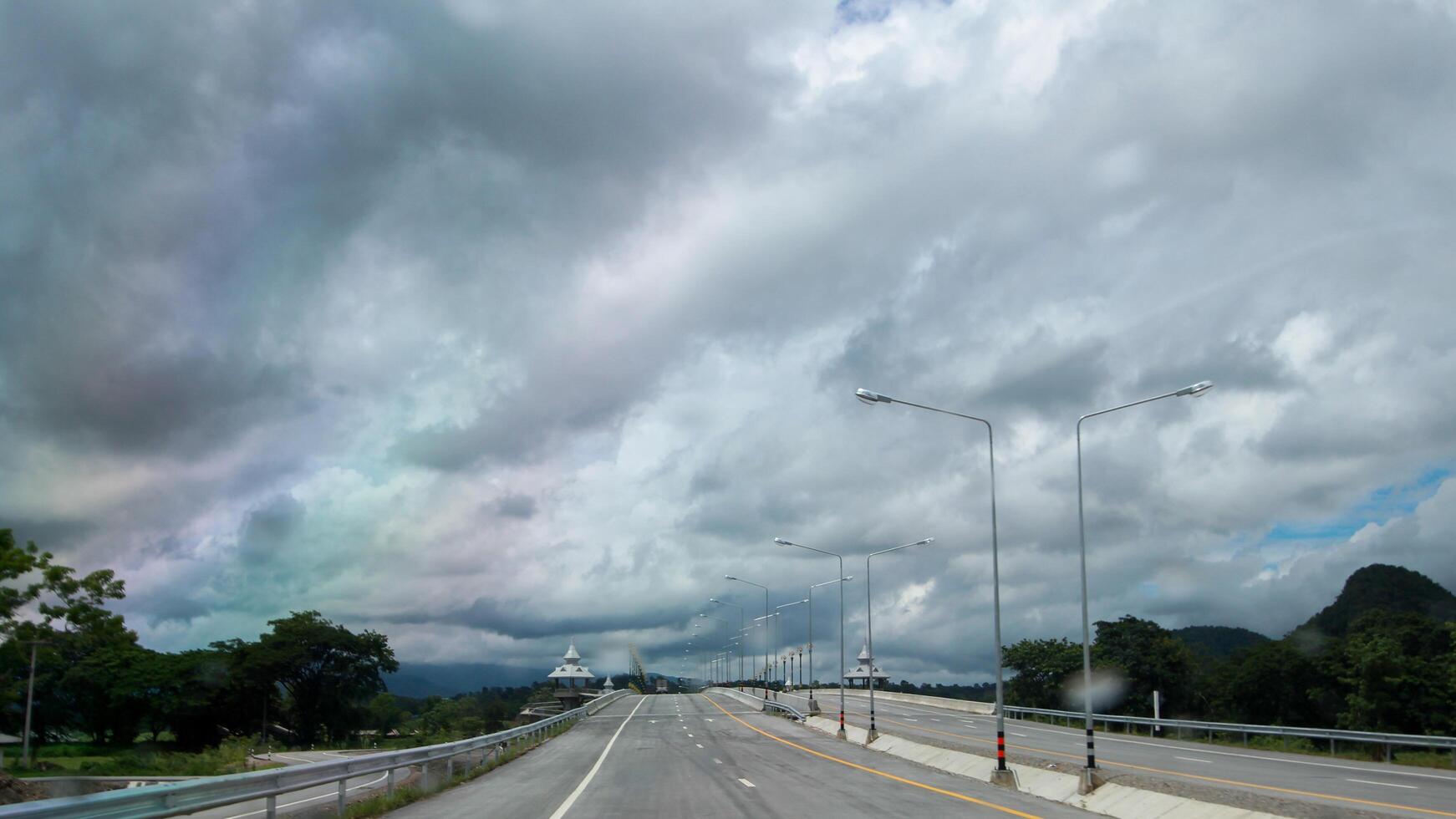 Blurry pictures of streets and rainstorms that are forming above the sky while driving make it a cautious drive. The concept of being more cautious when driving on the road during the rainy season. photo