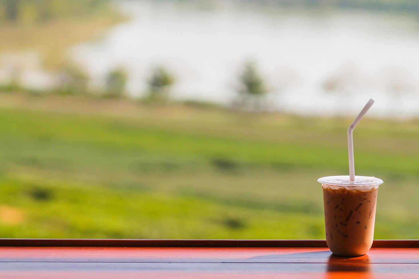 Iced coffee in plastic mugs on a wooden table by the window in the morning photo