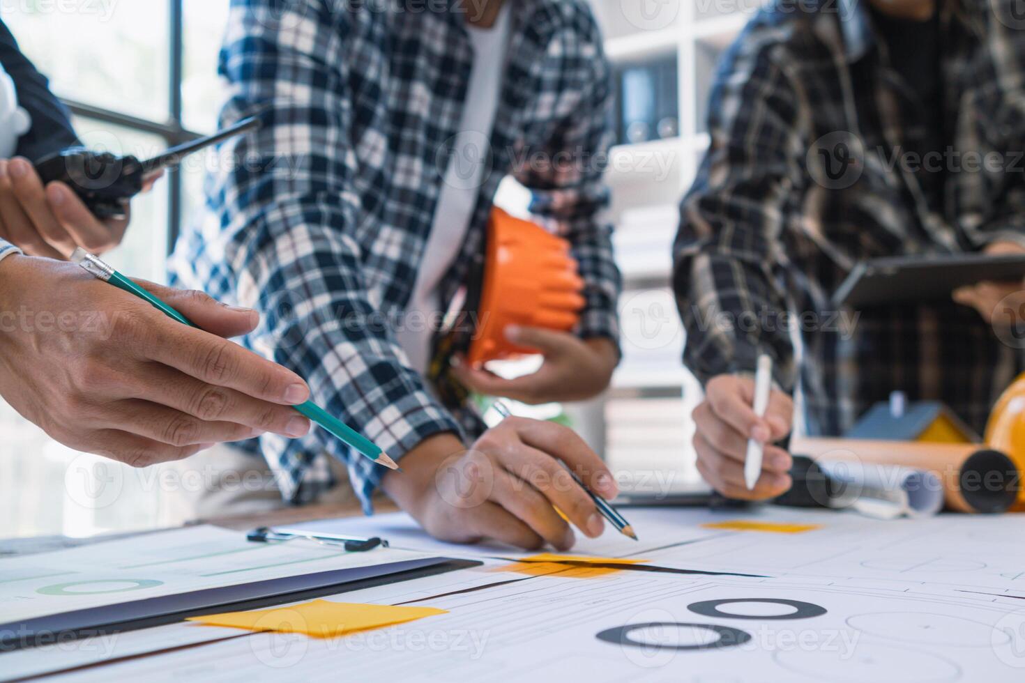 A team of engineers and architects discuss house plan design and estimate construction prices to suit the construction budget. Checking blueprints and documents with a team of engineers and architects photo