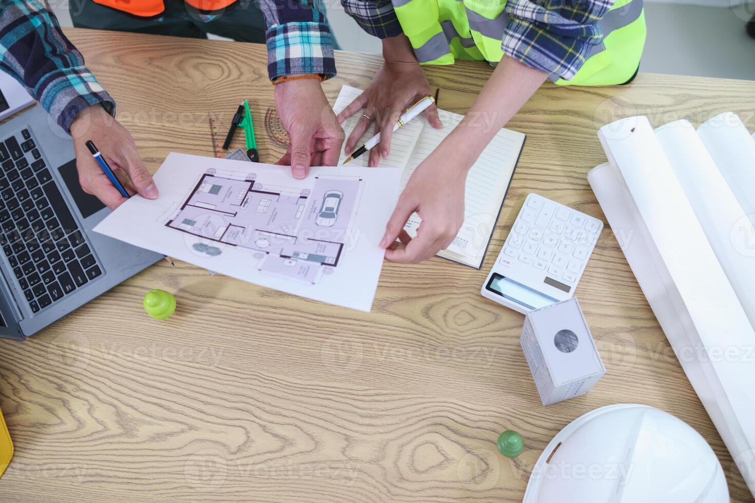 A team of engineers and architects discuss house plan design and estimate construction prices to suit the construction budget. Checking blueprints and documents with a team of engineers and architects photo