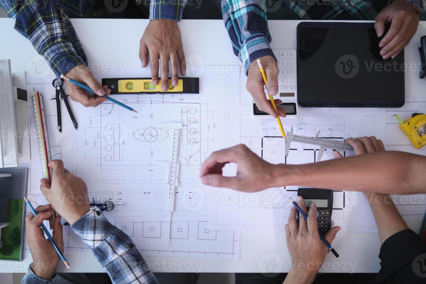 A team of engineers and architects discuss house plan design and estimate construction prices to suit the construction budget. Checking blueprints and documents with a team of engineers and architects photo