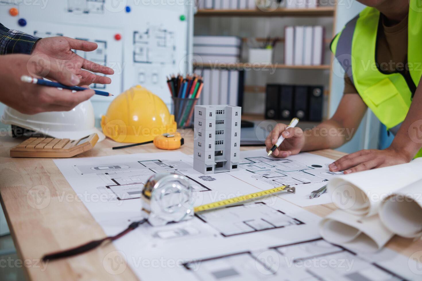 A team of engineers and architects discuss house plan design and estimate construction prices to suit the construction budget. Checking blueprints and documents with a team of engineers and architects photo