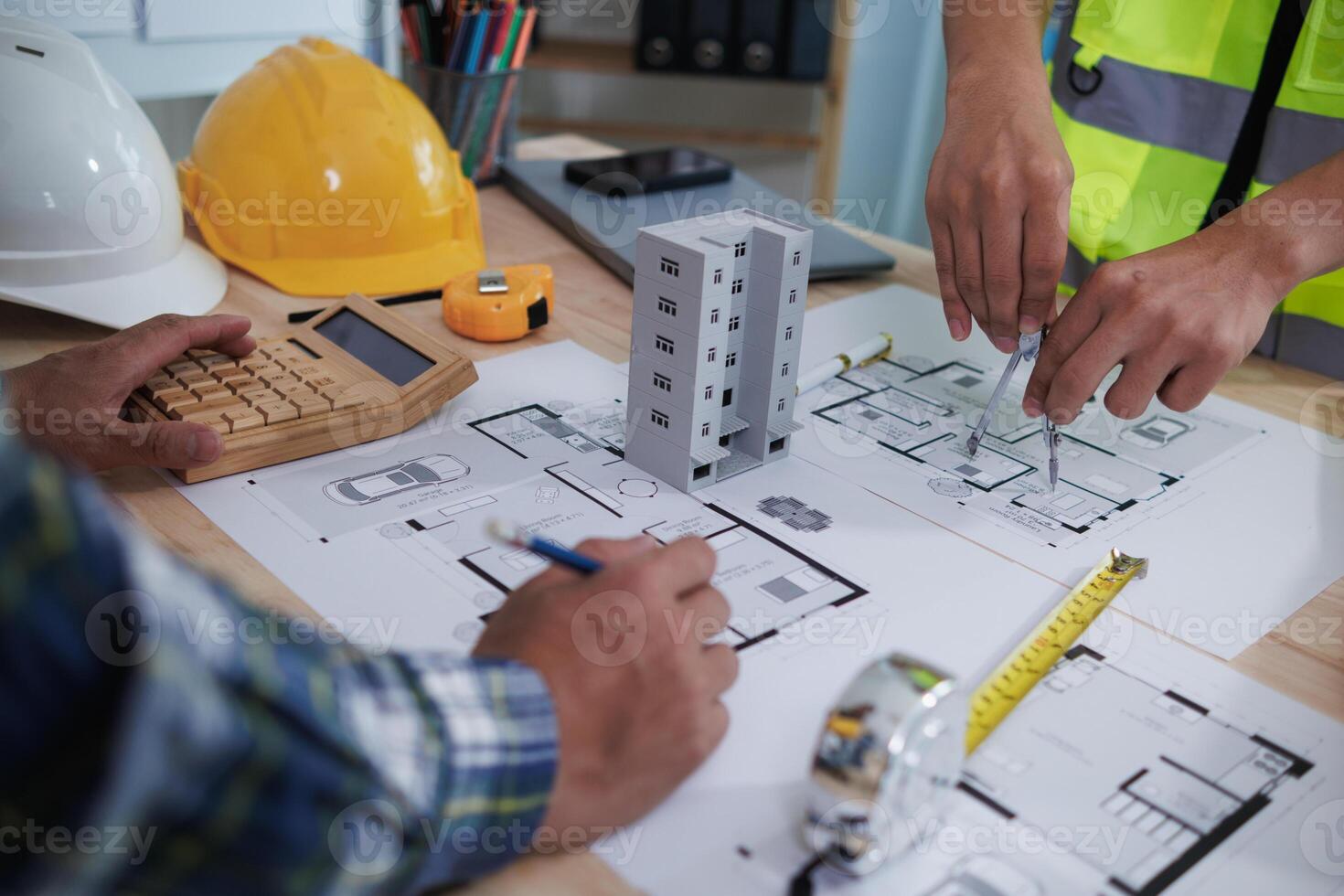 A team of engineers and architects discuss house plan design and estimate construction prices to suit the construction budget. Checking blueprints and documents with a team of engineers and architects photo