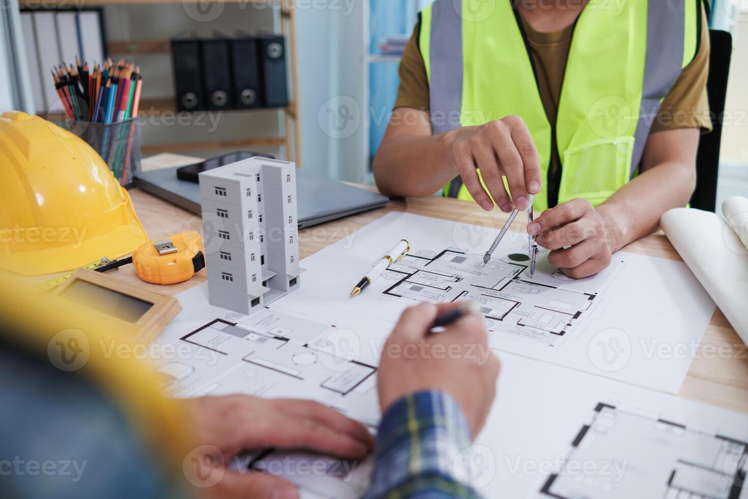 A team of engineers and architects discuss house plan design and estimate construction prices to suit the construction budget. Checking blueprints and documents with a team of engineers and architects photo