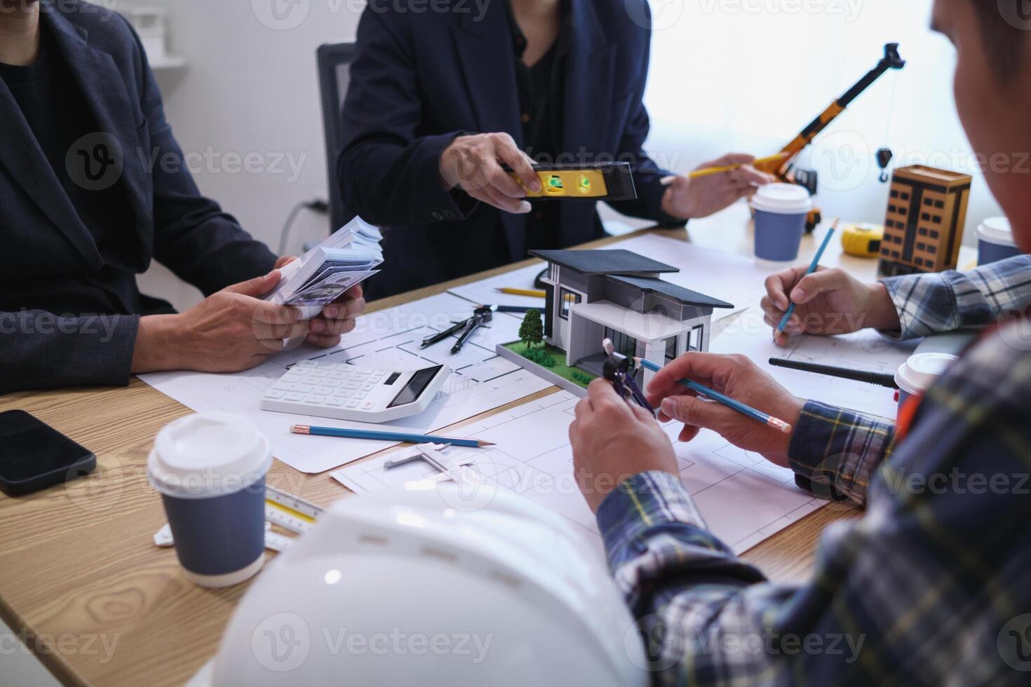 team of engineers and architects discuss house plan design and estimate construction prices to suit the construction budget. Checking blueprints and documents with a team of engineers and architects photo