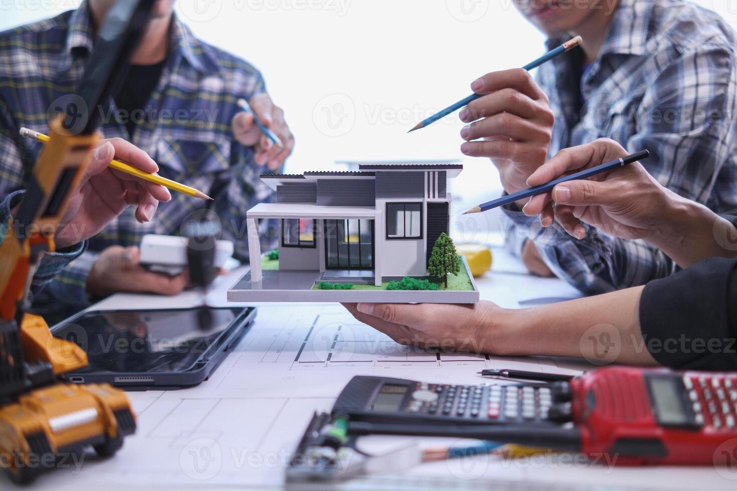 team of engineers and architects discuss house plan design and estimate construction prices to suit the construction budget. Checking blueprints and documents with a team of engineers and architects photo