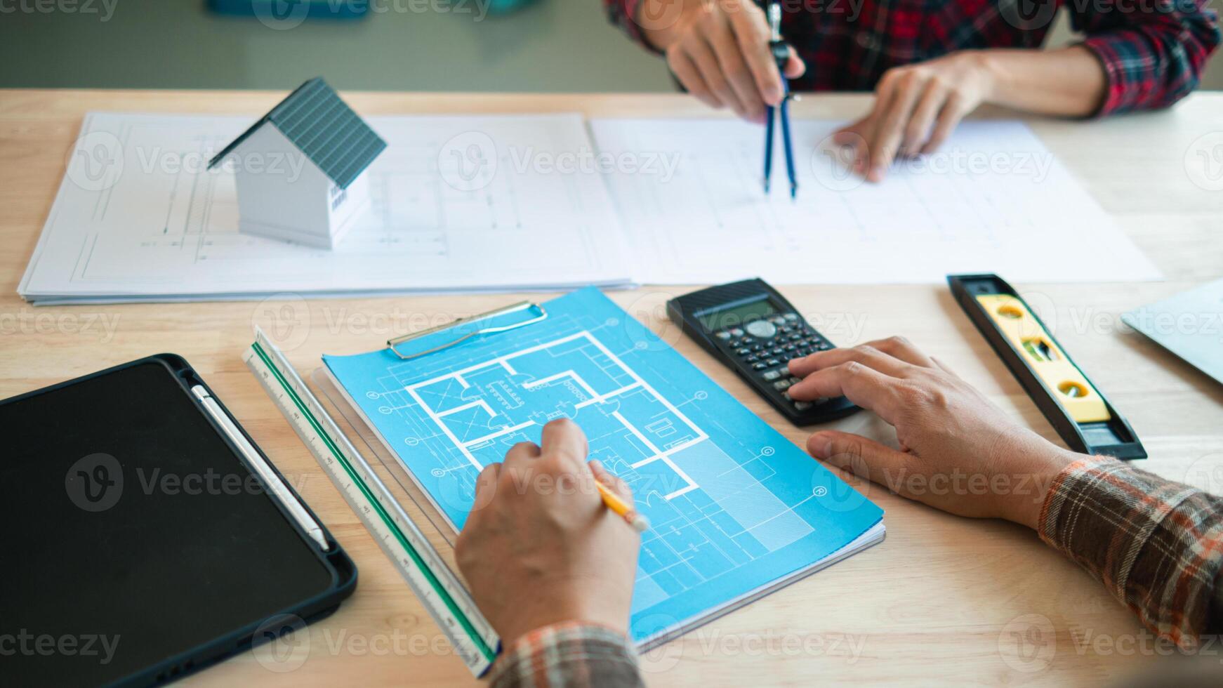 A team of engineers and architects discuss house plan design and estimate construction prices to suit the construction budget. Checking blueprints and documents with a team of engineers and architects photo