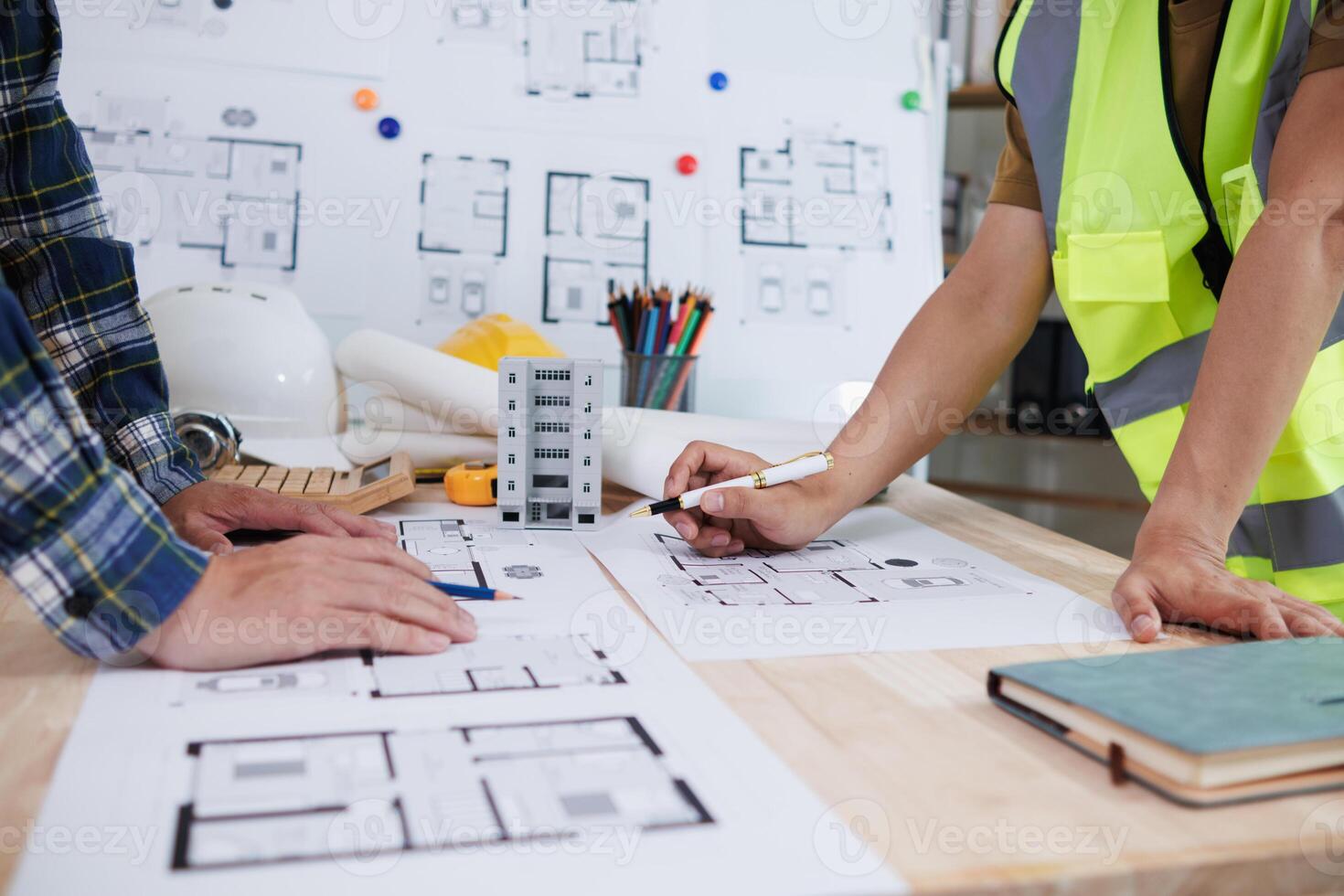 A team of engineers and architects discuss house plan design and estimate construction prices to suit the construction budget. Checking blueprints and documents with a team of engineers and architects photo