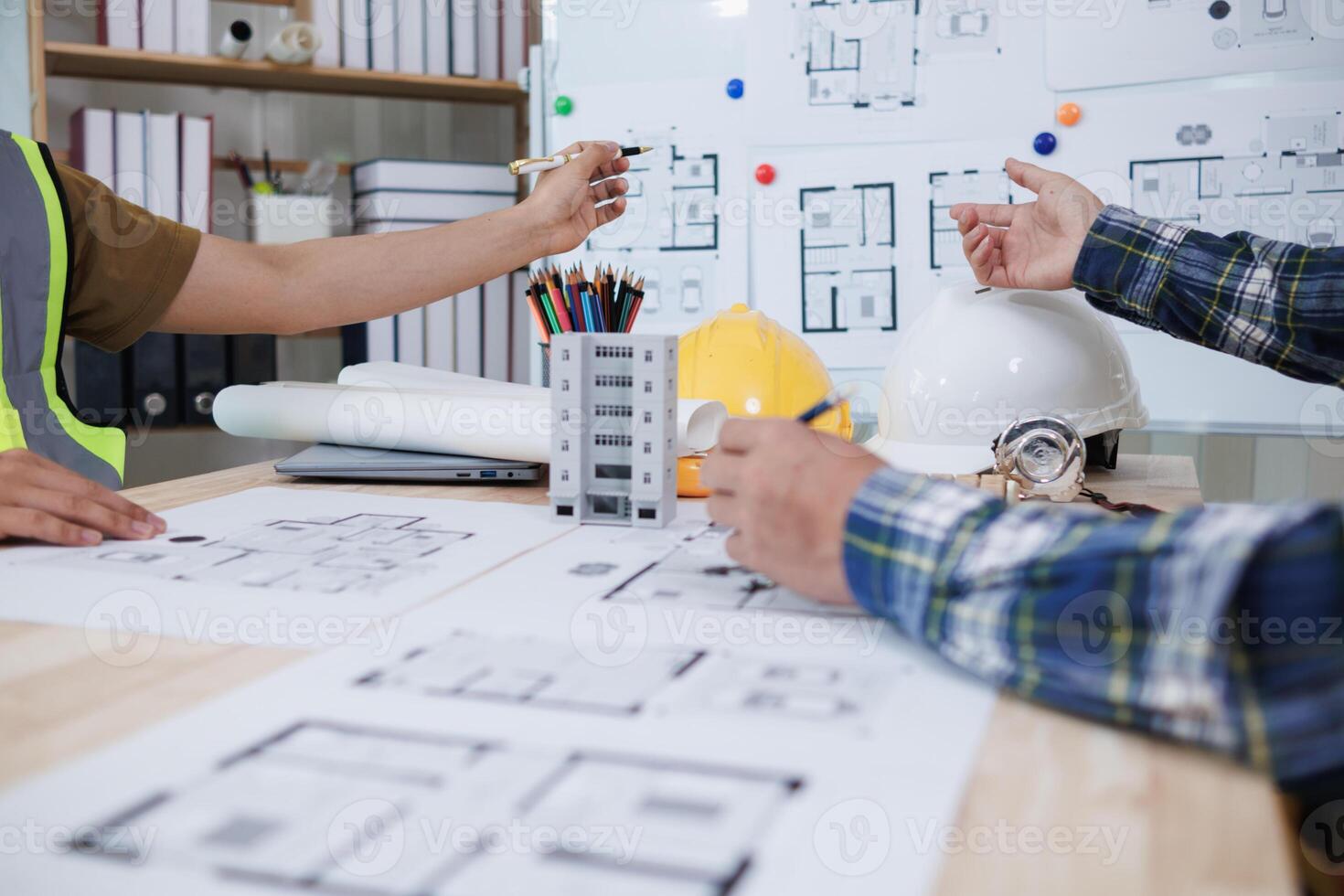 A team of engineers and architects discuss house plan design and estimate construction prices to suit the construction budget. Checking blueprints and documents with a team of engineers and architects photo