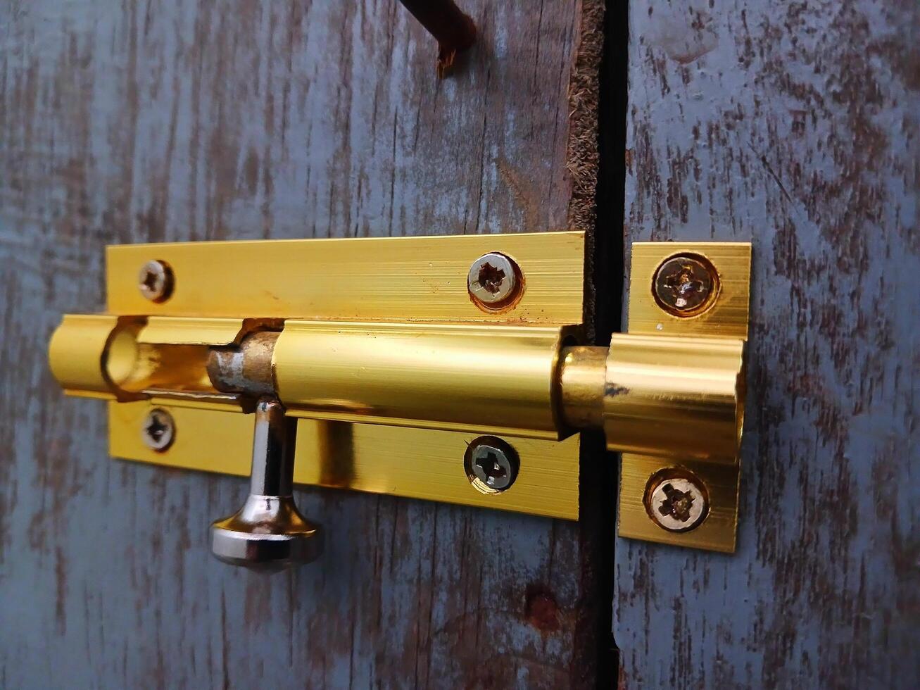 Gold color manual door lock with light wooden door photo