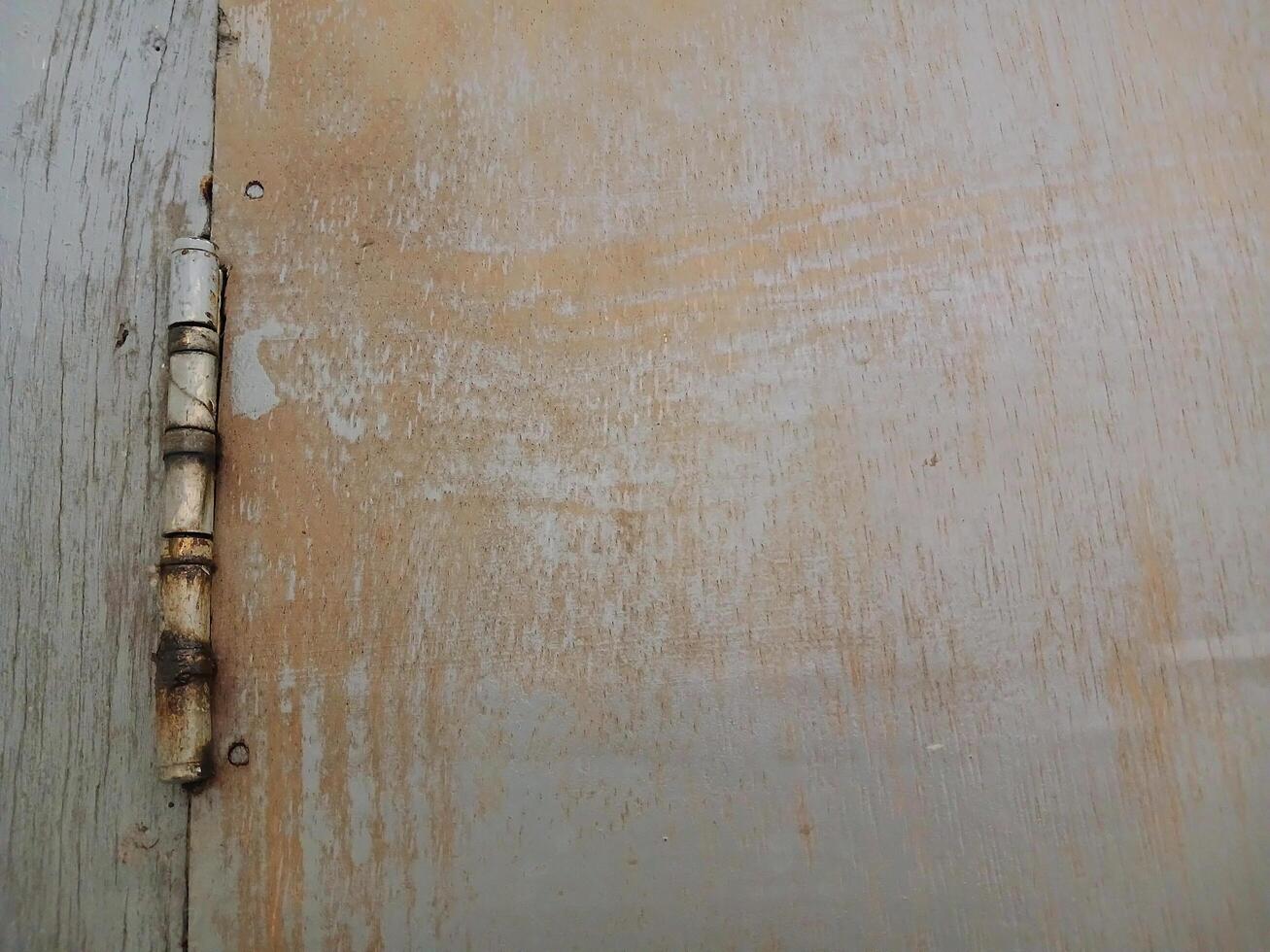 Rusty door hinges cut into the wooden door, connecting fasteners screwed in, construction parts. photo