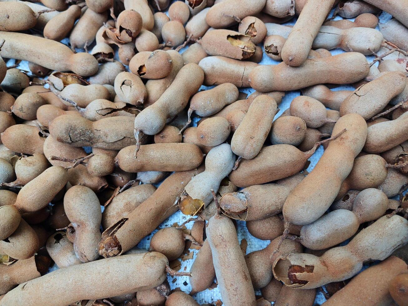 Ripe tamarind fruit and some tamarind seeds on a wooden woven board. photo