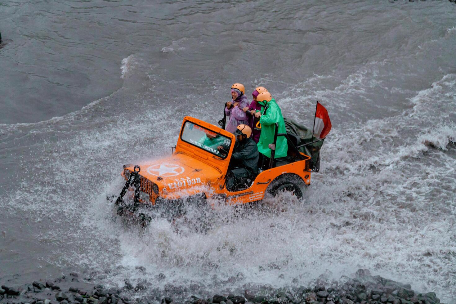 Sleman, Yogyakarta, Indonesia, 2024 - Crossing the river in a high-speed jeep until the water splashes in all directions and wets the passengers. Offroad driving tourist jeep during holiday season photo