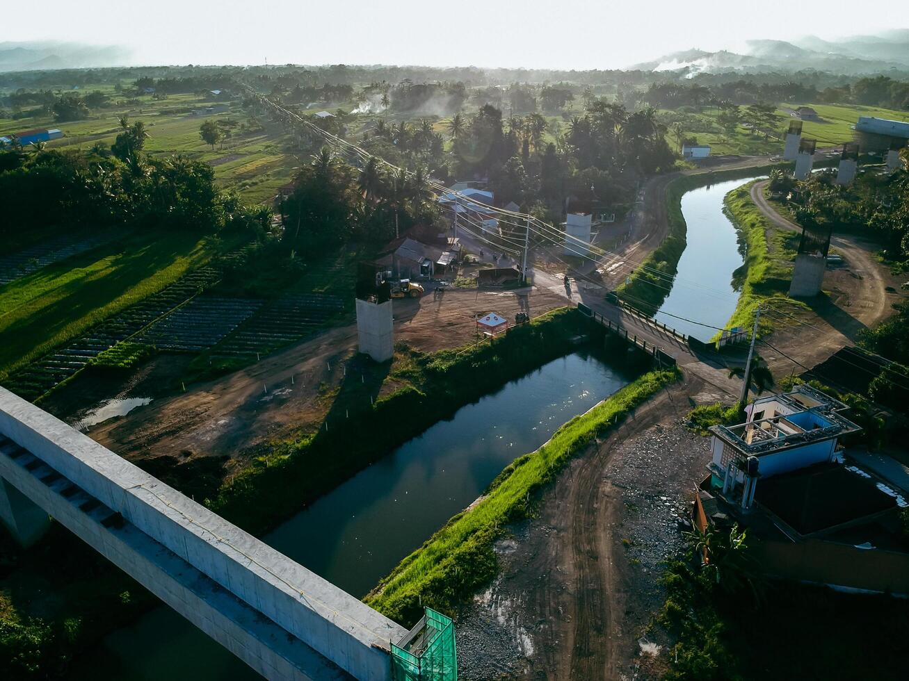 Sleman, Yogyakarta, Indonesia, 2024 - Toll road construction project over the Mataram ditch. A toll bridge is being built over the water flow so as not to displace rice fields and settlements photo