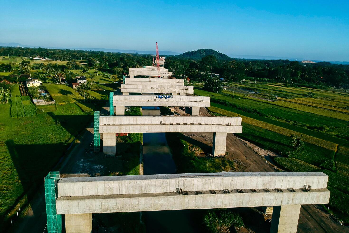 Sleman, Yogyakarta, Indonesia, 2024 - Toll road construction project over the Mataram ditch. A toll bridge is being built over the water flow so as not to displace rice fields and settlements photo