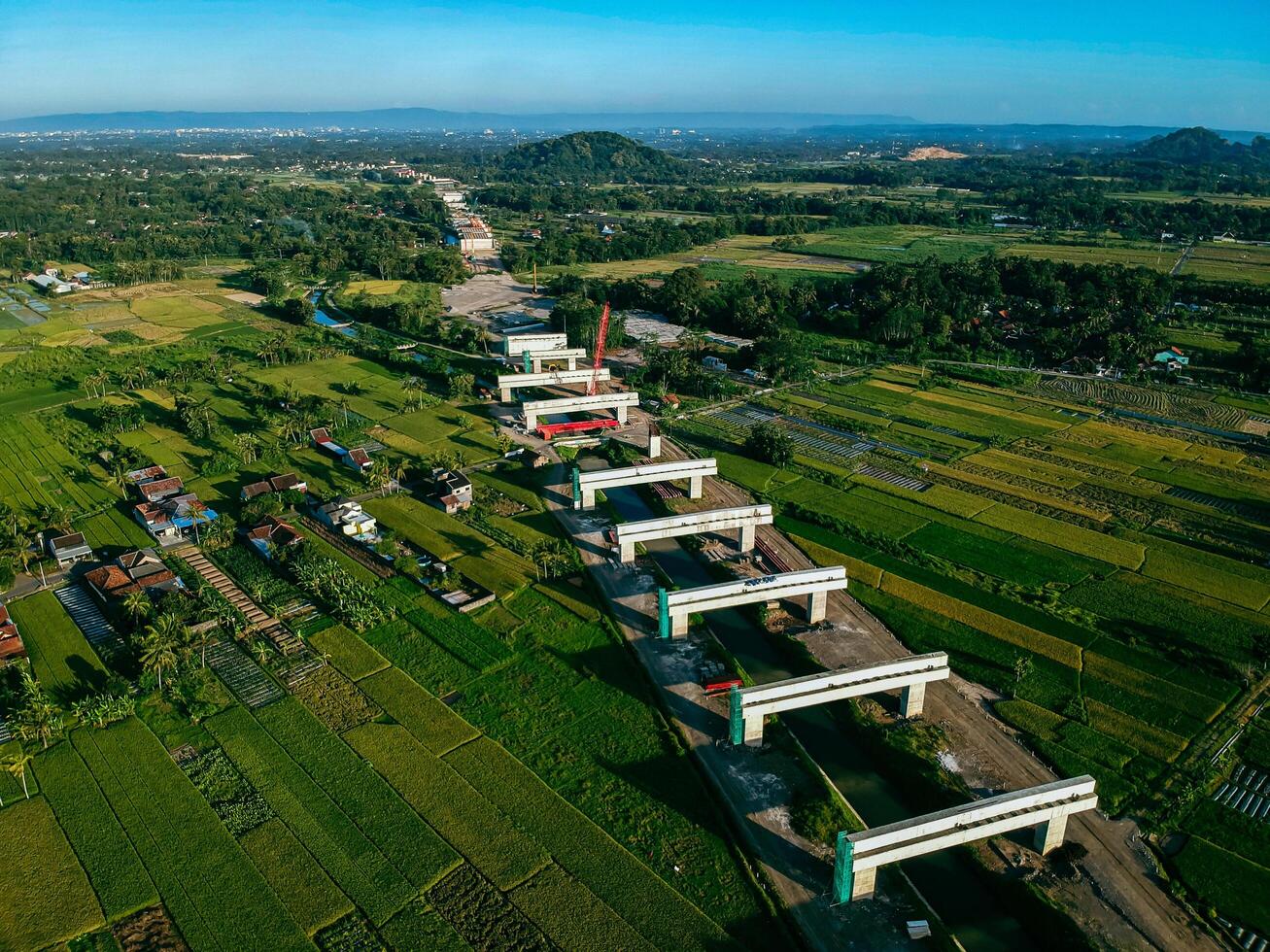 Sleman, Yogyakarta, Indonesia, 2024 - Toll road construction project over the Mataram ditch. A toll bridge is being built over the water flow so as not to displace rice fields and settlements photo