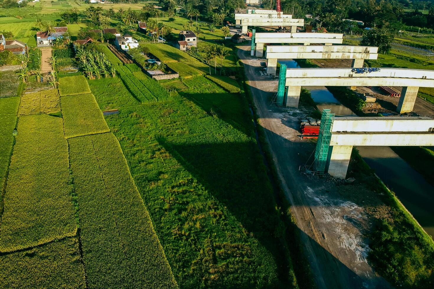 Sleman, Yogyakarta, Indonesia, 2024 - Toll road construction project over the Mataram ditch. A toll bridge is being built over the water flow so as not to displace rice fields and settlements photo