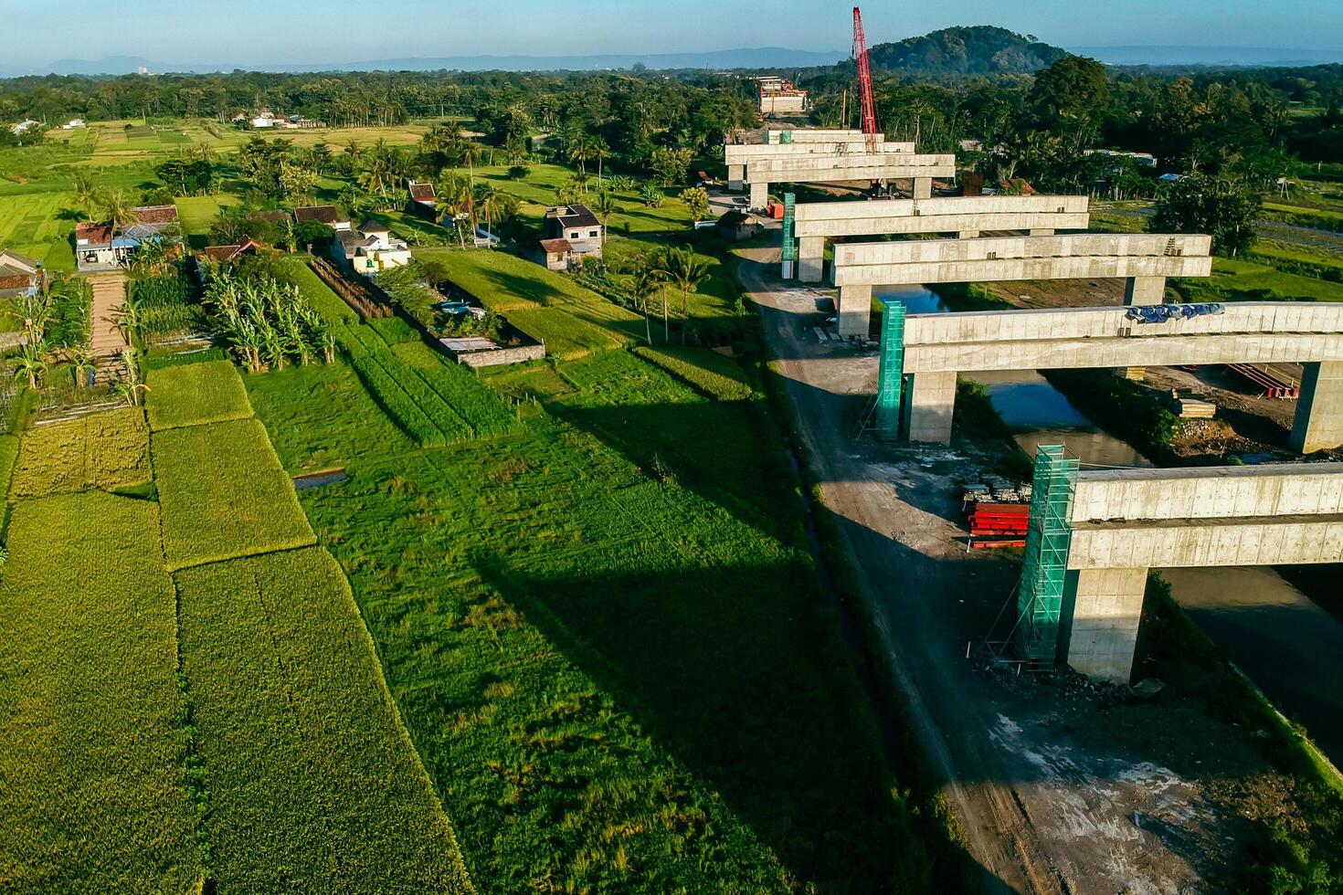 Sleman, Yogyakarta, Indonesia, 2024 - Toll road construction project over the Mataram ditch. A toll bridge is being built over the water flow so as not to displace rice fields and settlements photo