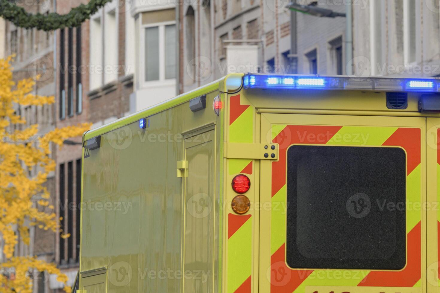 An ambulance on a city street, a fragment of the corps with the light signal on. photo