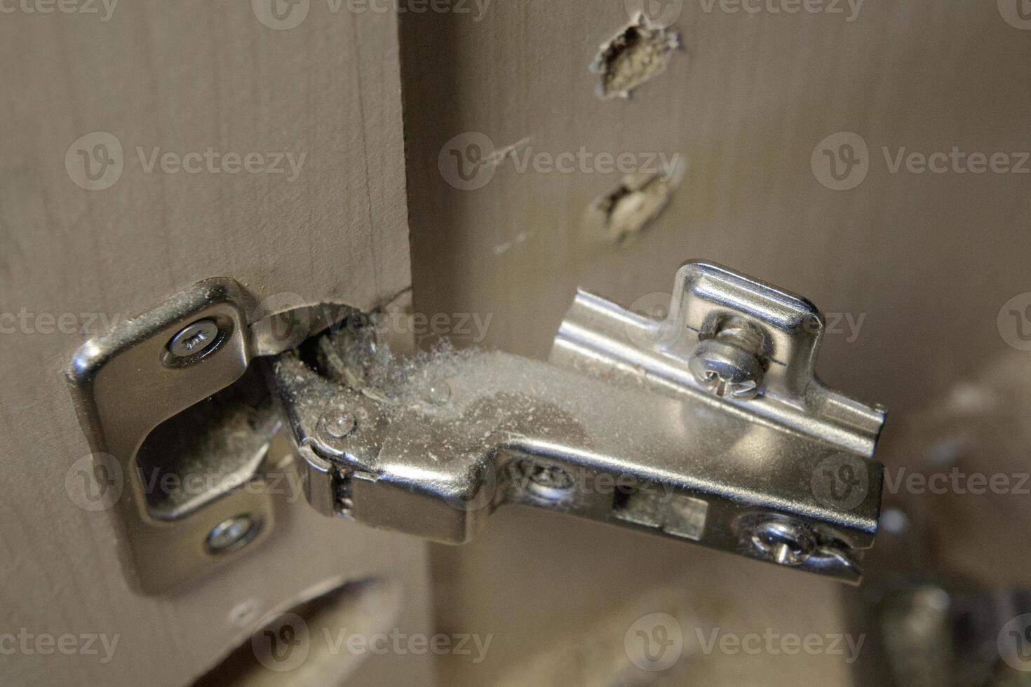 Torn-out hinge of furniture fittings. hinge fixed on a modern cabinet. Breakage of furniture fittings. Screw holes photo