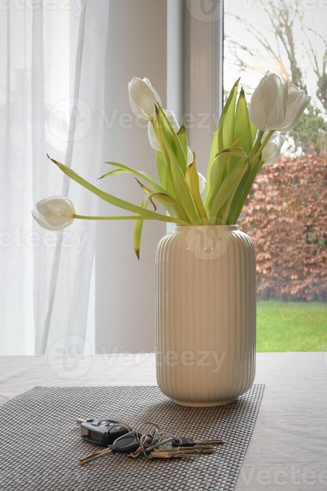 Flowers withering in a vase and keys left on the table. Vertical format. Concept photo