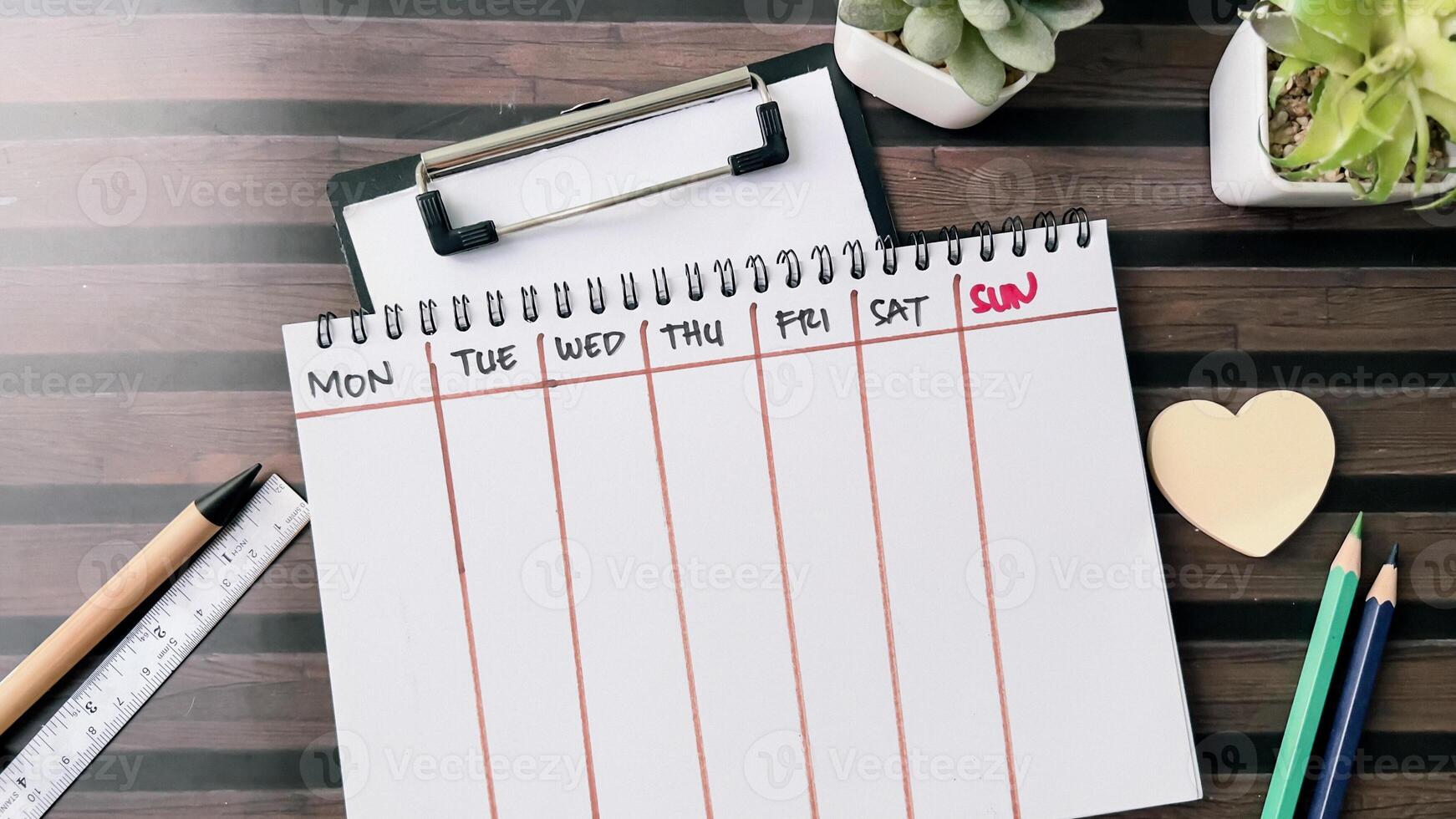 Concept of Weekly Calendar write on book isolated on Wooden Table. photo
