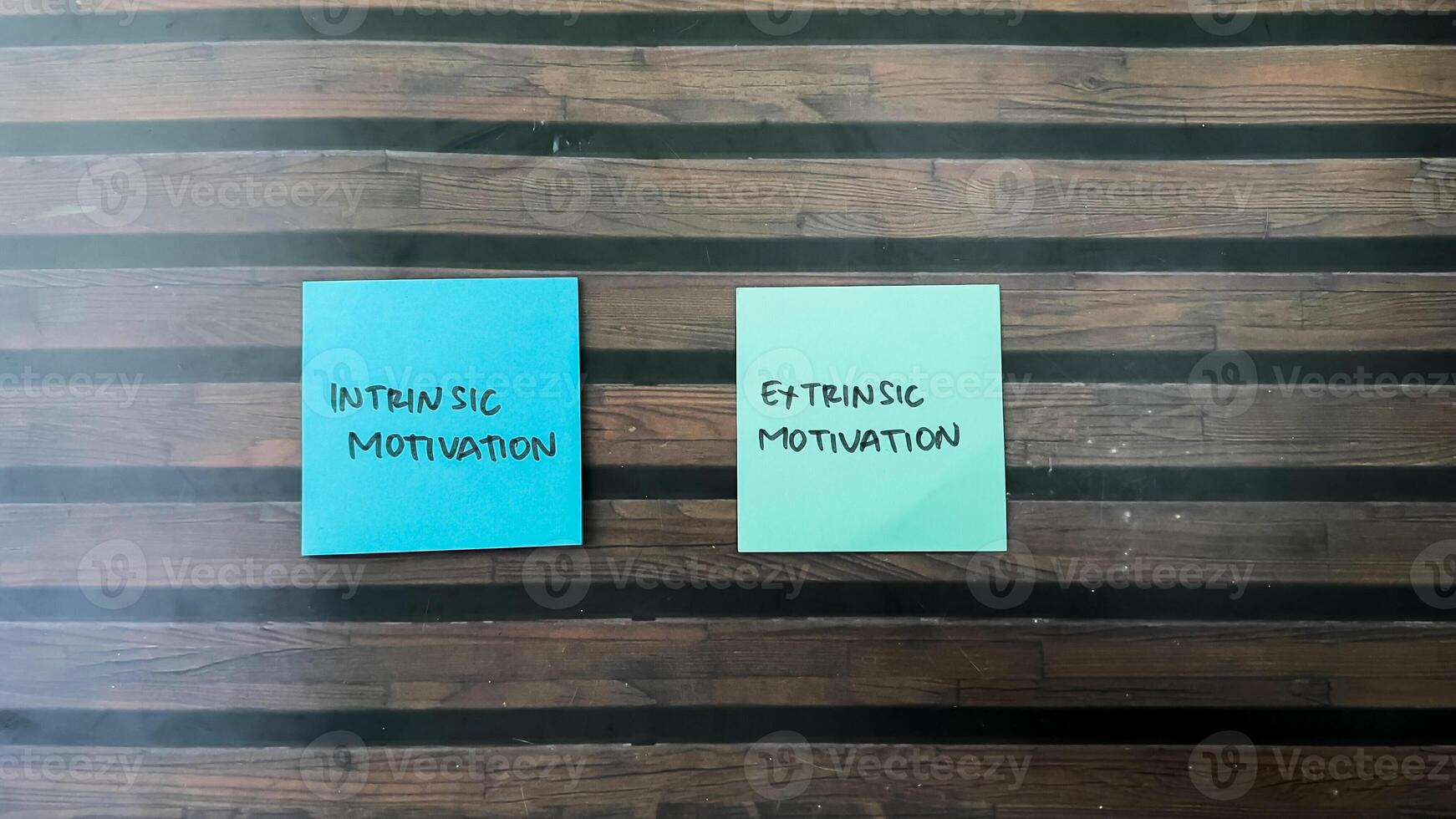 Concept of Intrinsic Motivation or Extrinsic Motivation write on sticky notes isolated on Wooden Table. photo