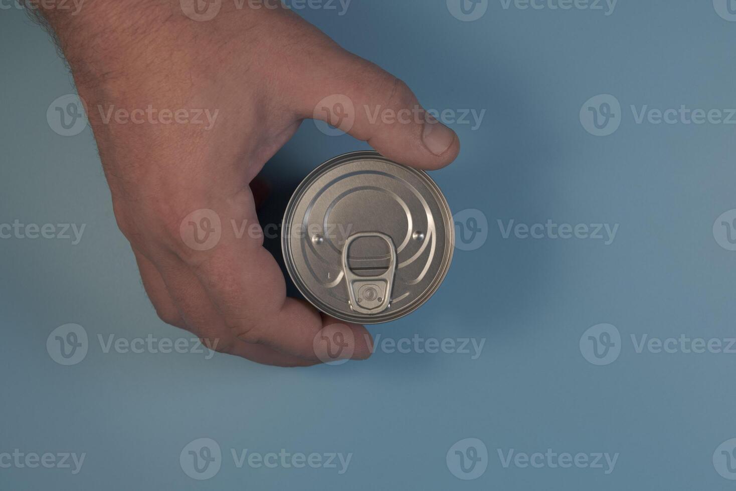 A tin can in the man's hand. Flatlay on a blue background close-up photo