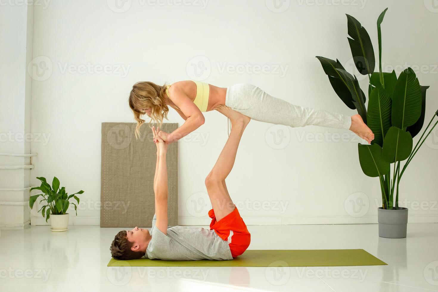 A guy in sportswear, lies on a sports mat, does yoga in a pair with a slender woman, doing exercises with support. photo