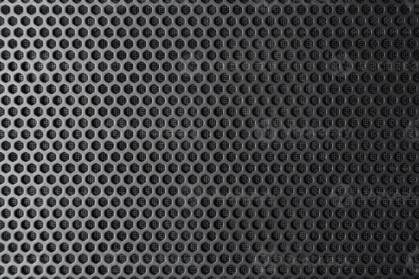 Industrial background. Black metal surface with regular round holes as texture photo