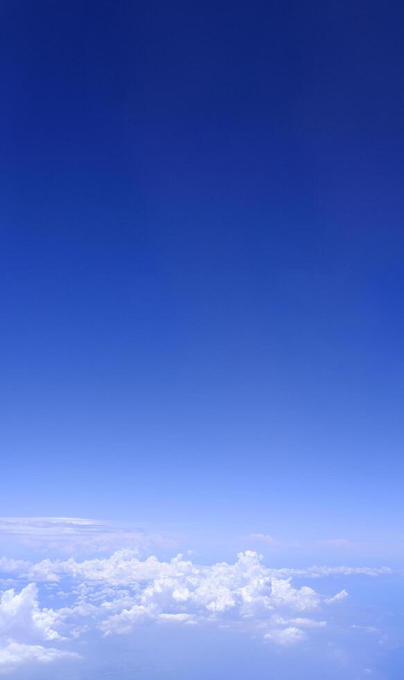 Vertical gradient blue sky with white fluffy clouds photo