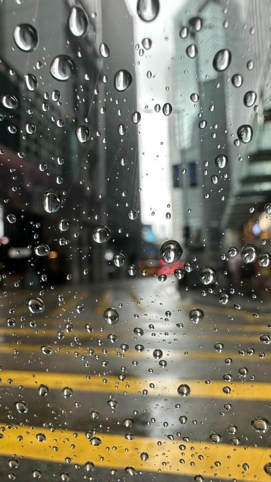 Rainy days, rain drops on window, rainy weather, rain background with blurred street background photo