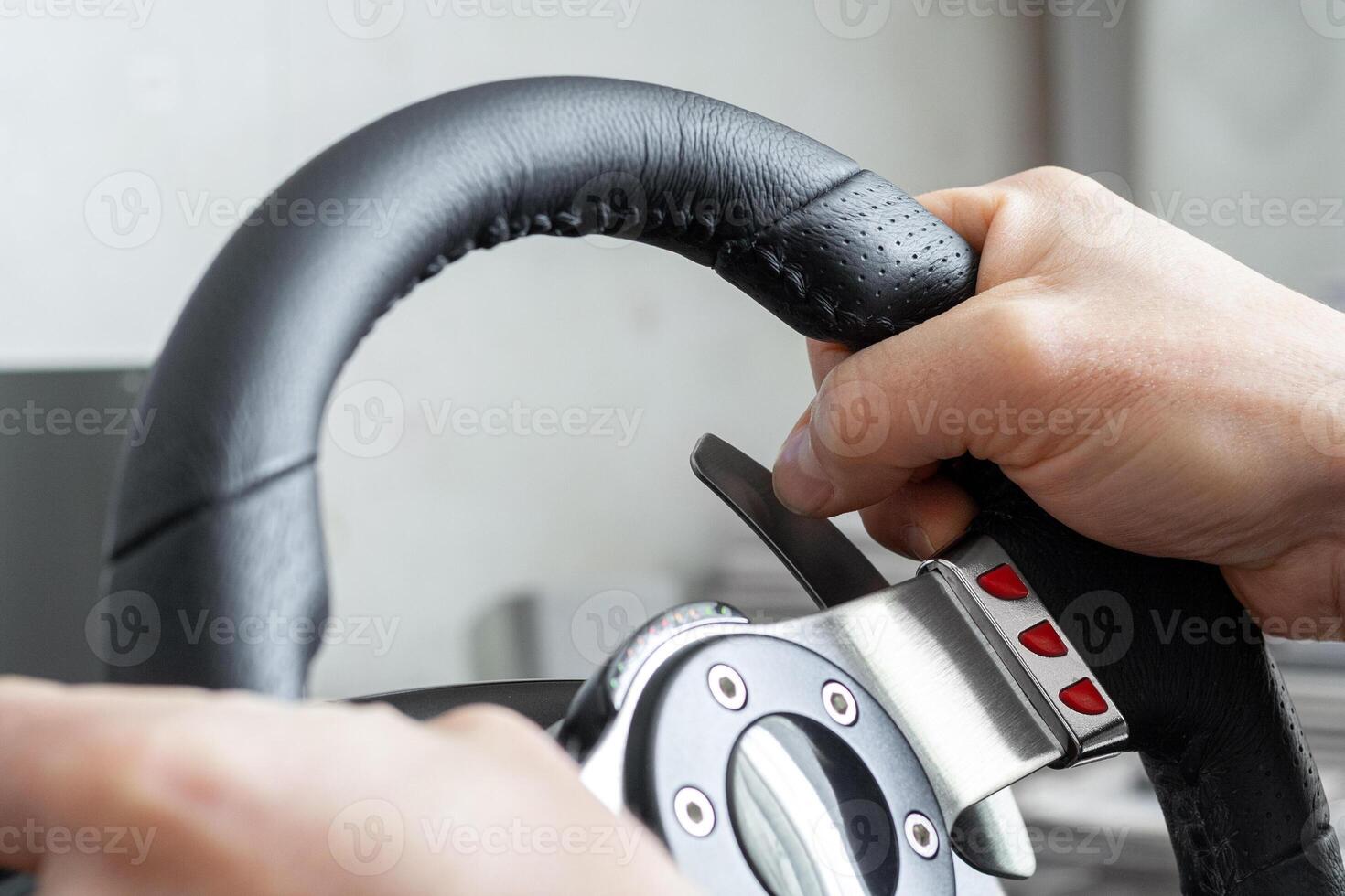 View on a man's hands playing a racing simulator on a steering wheel photo
